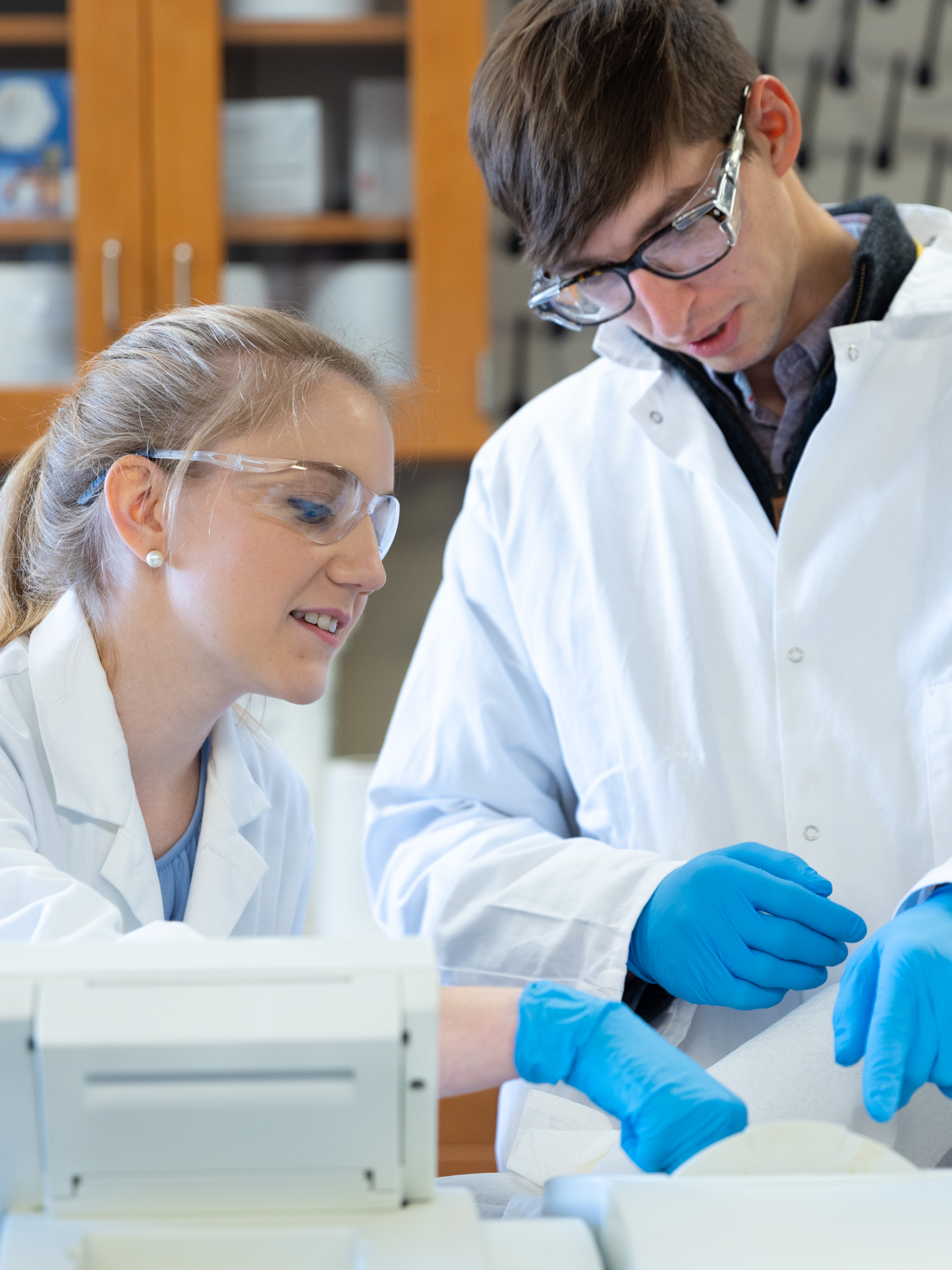 Two young scientists in protective clothing look down at papers at the Business Park in Lawrence