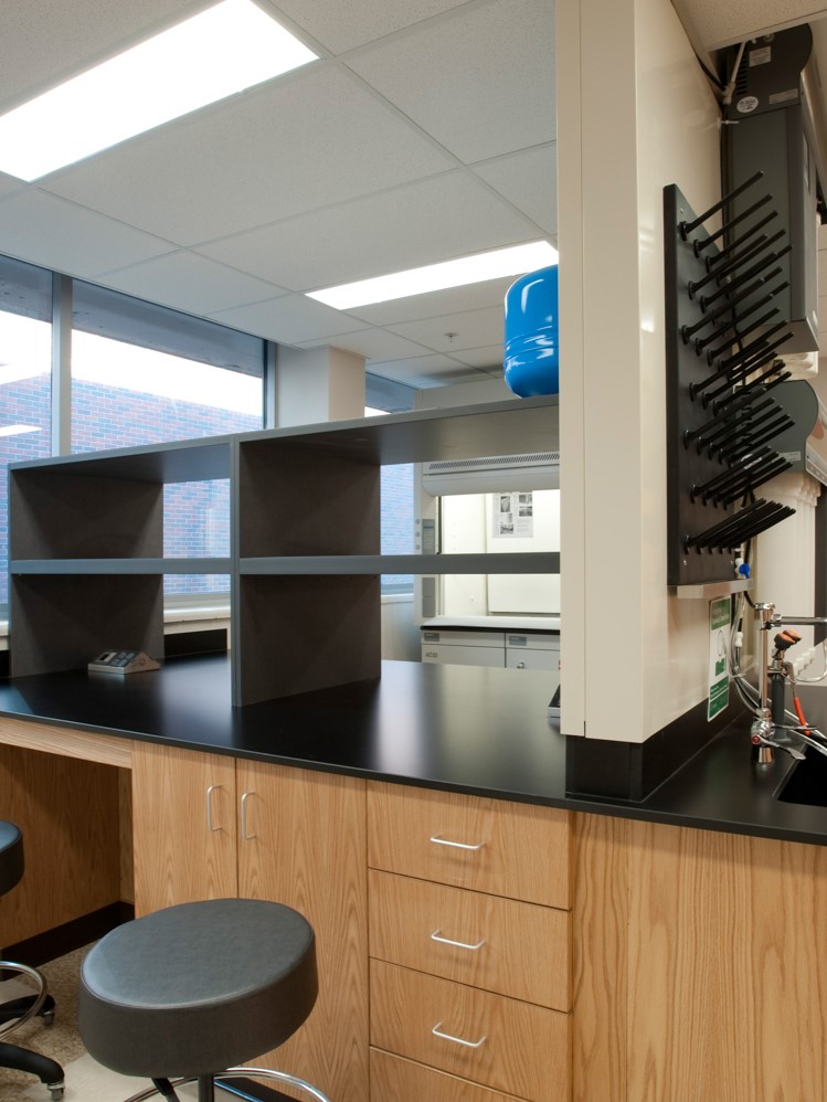 A man in a labcoat and other personal with protective equipment holds a long pipette in a lab at the Bioscience and Technology Business Incubator in Lawrence, KS.